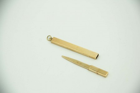 Palito em ouro amarelo com relevos e argola de suspensão.